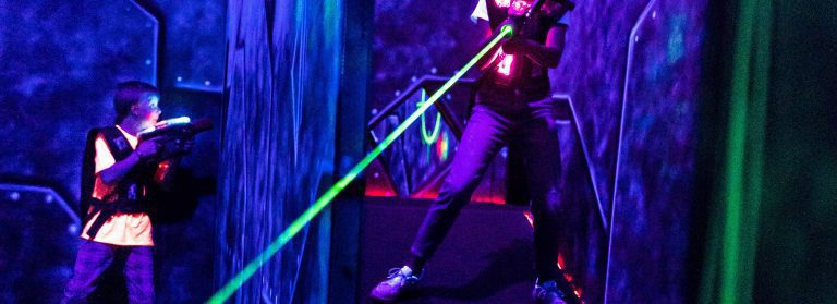 Zwei Kinder in der Lasertag Arena zwischen ihnen eine Wand.