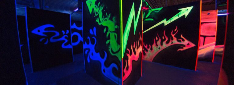 Eine schwarze Wand in der Lasertag-Arena mit Malereien von Feuer, Wasser und Pflanzen.